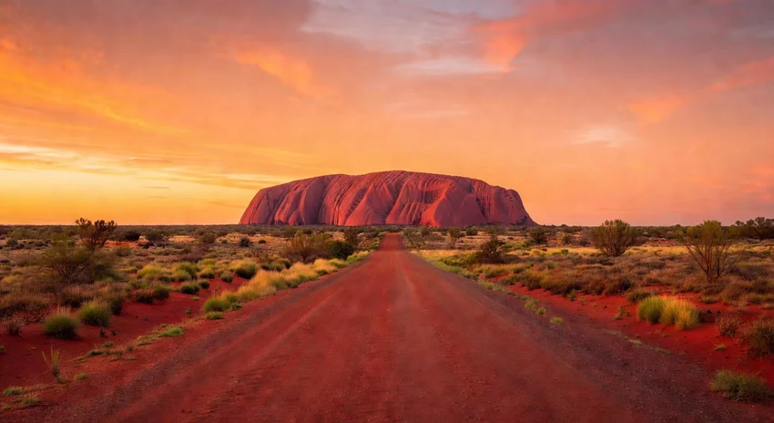 Route vers Uluru dans l'Outback australien au coucher du soleil